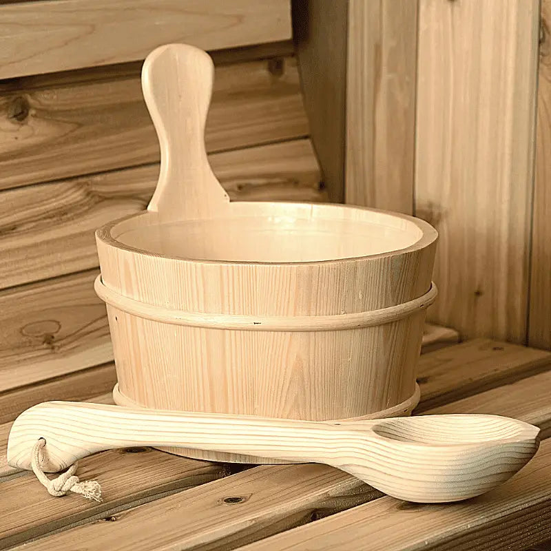 Wooden sauna bucket and ladle on a wooden surface