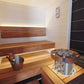 Wooden sauna interior with a metal bucket and wooden bench by Finnish Sauna Builders