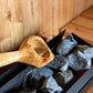 Homecraft H-Series Electric Sauna Heater Wooden spoon over hot stones in a sauna setting