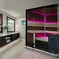 Modern bathroom with dark wood cabinets, pink LED lighting, and a freestanding bathtub.